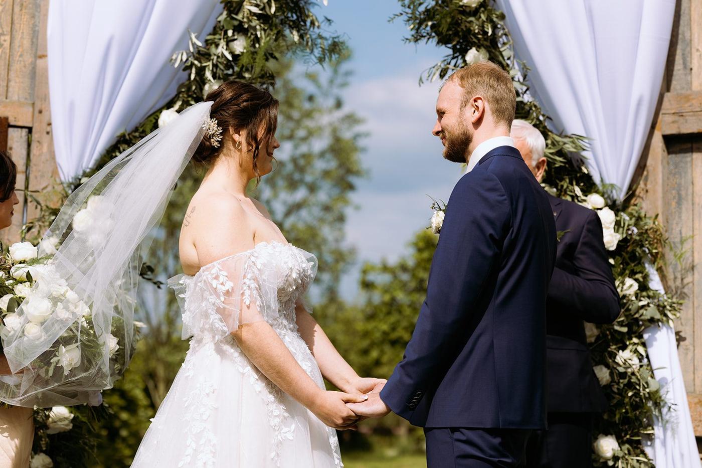 Bruidspaar tijdens de ceremonie onder een gestylde backdrop met bloemen